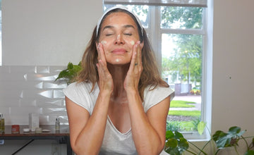 a woman applying skincare to her face, looking relaxed
