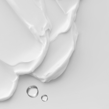 an image of white cream layered with a couple drops of serum
