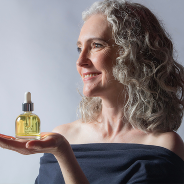 a woman with grey hair holding the NOURISHING OIL