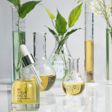an image of the IN YOUR FACE NOURISHING OIL surrounded by beakers of oil and botanicals