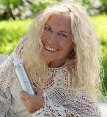an older woman holding CREAMY BODY OIL and smiling