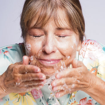 an image of a woman splashing water on her face with her hands