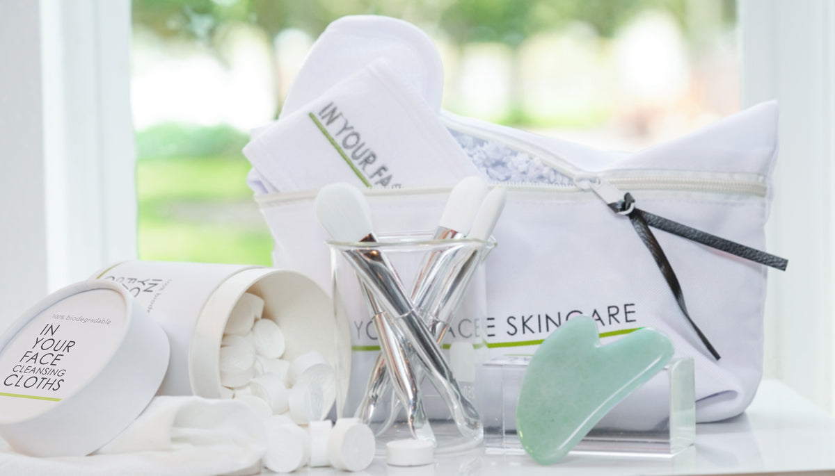 an image of various IN YOUR FACE SKINCARE accessories and tools, like the cleansing cloths, a mask brush, a gua sha stone and makeup bag