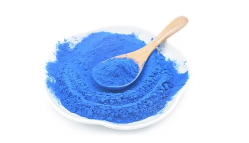 an image of blue spirulina, a blue powder with a wooden spoon