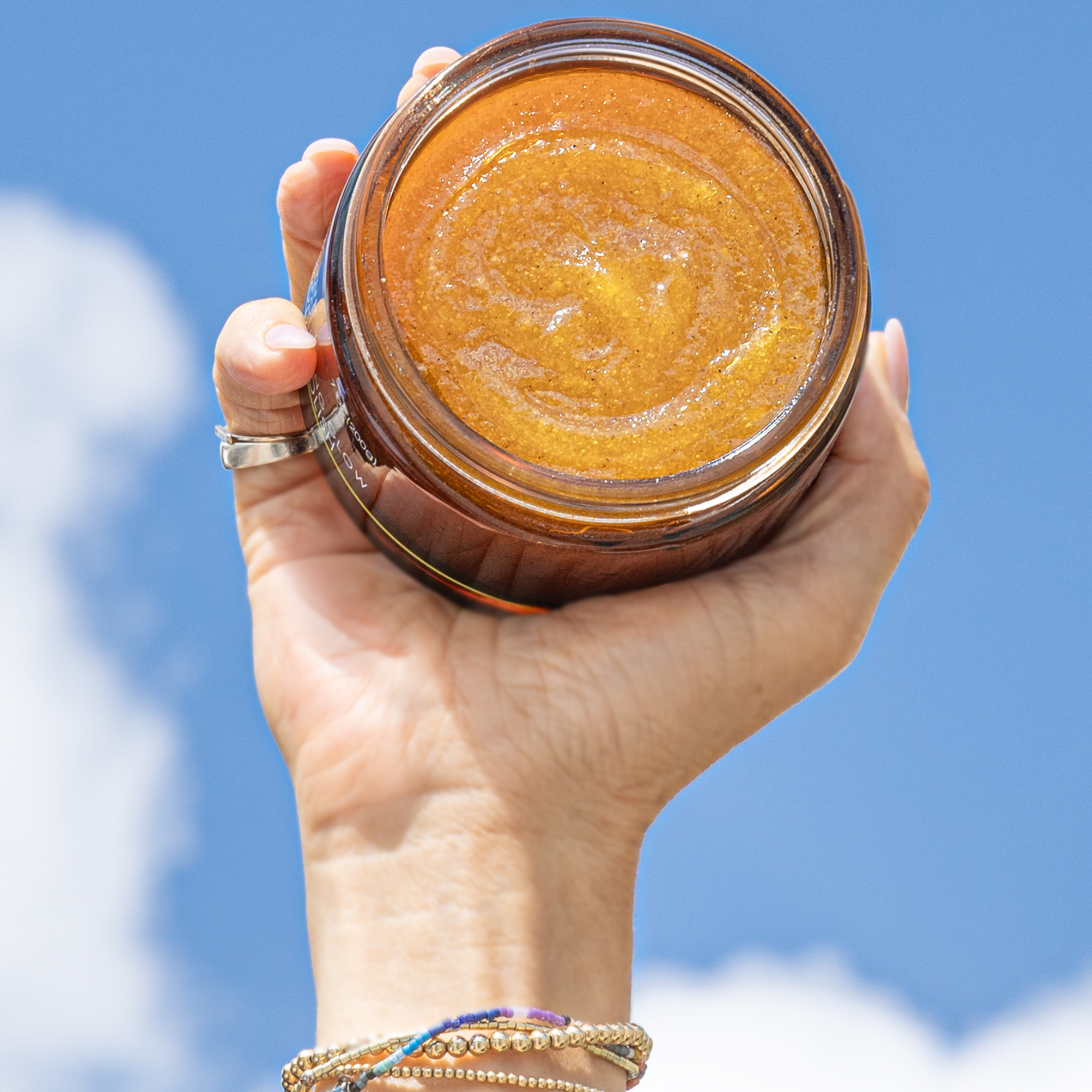 hand holding the body polish up to sky, showing the texture