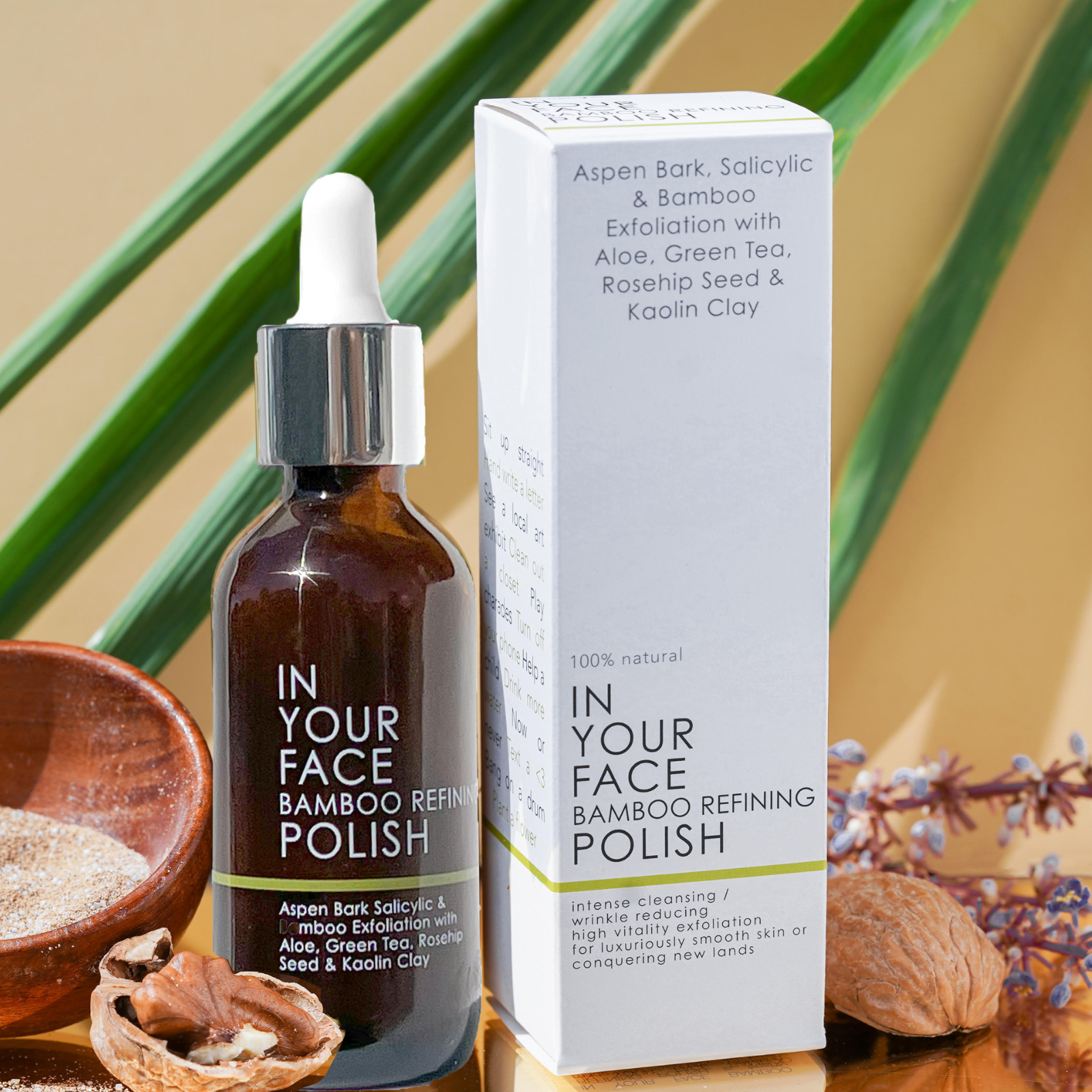 an image of the BAMBOO REFINING POLISH on a white background with a small shadow under it. On the bottle it says "Aspen Bark Salicylic & Bamboo Exfoliation with Aloe, Green Tea, Rosehip Seed & Kaolin Clay". The bottle is a dark brown opaque color. It's next to the box of the POLISH. The box says at the bottom: "100% natural IN YOUR FACE BAMBOO REFINING POLISH. Intense cleansing / wrinkle reducing, high vitaity exfoliation for luxuriously smooth skin or conquering new lands".