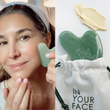 woman holding the GUA SHA to her cheek.