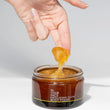 jar of exfoliating glow body polish with fingers dipping into it