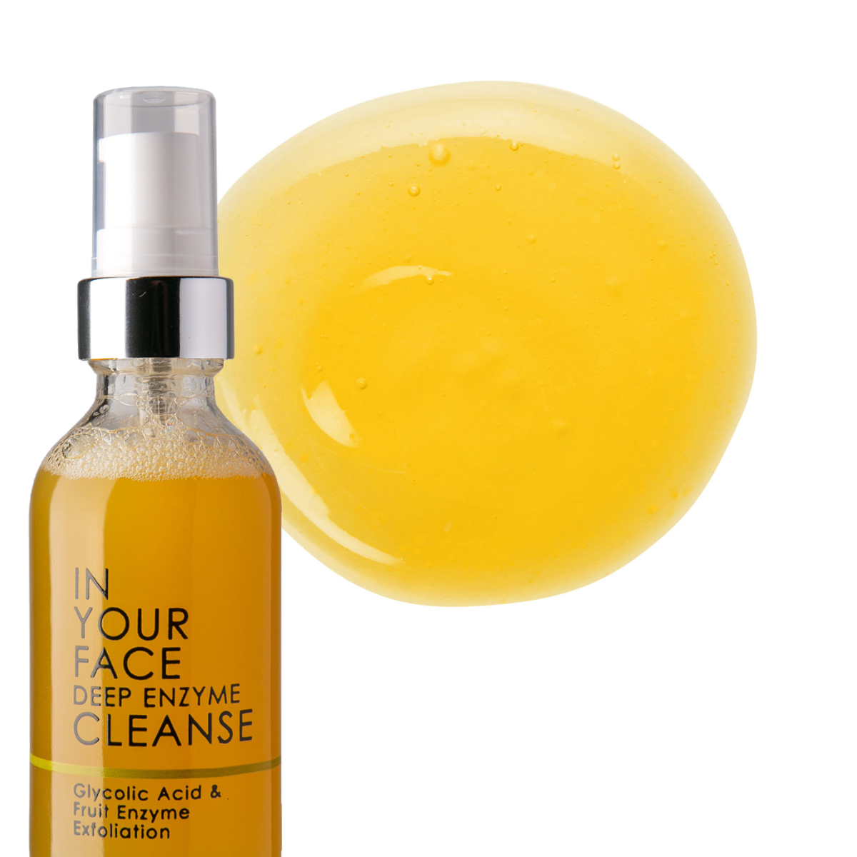 a bottle of IN YOUR FACE DEEP ENZYME CLEANSE on a white background. The bottle also says "Glycolic Acid & Fruit Enzyme Exfoliation". It's with a pump dispenser and the product inside is an orange color. Next to the bottle is a dollop of the product and it is an orange color with a couple small bubbles.