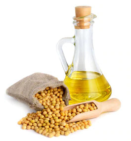 carafe of oil and pile of soybeans on white background