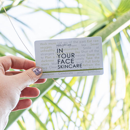 GIFT CARD held up against a bunch of palm leaves