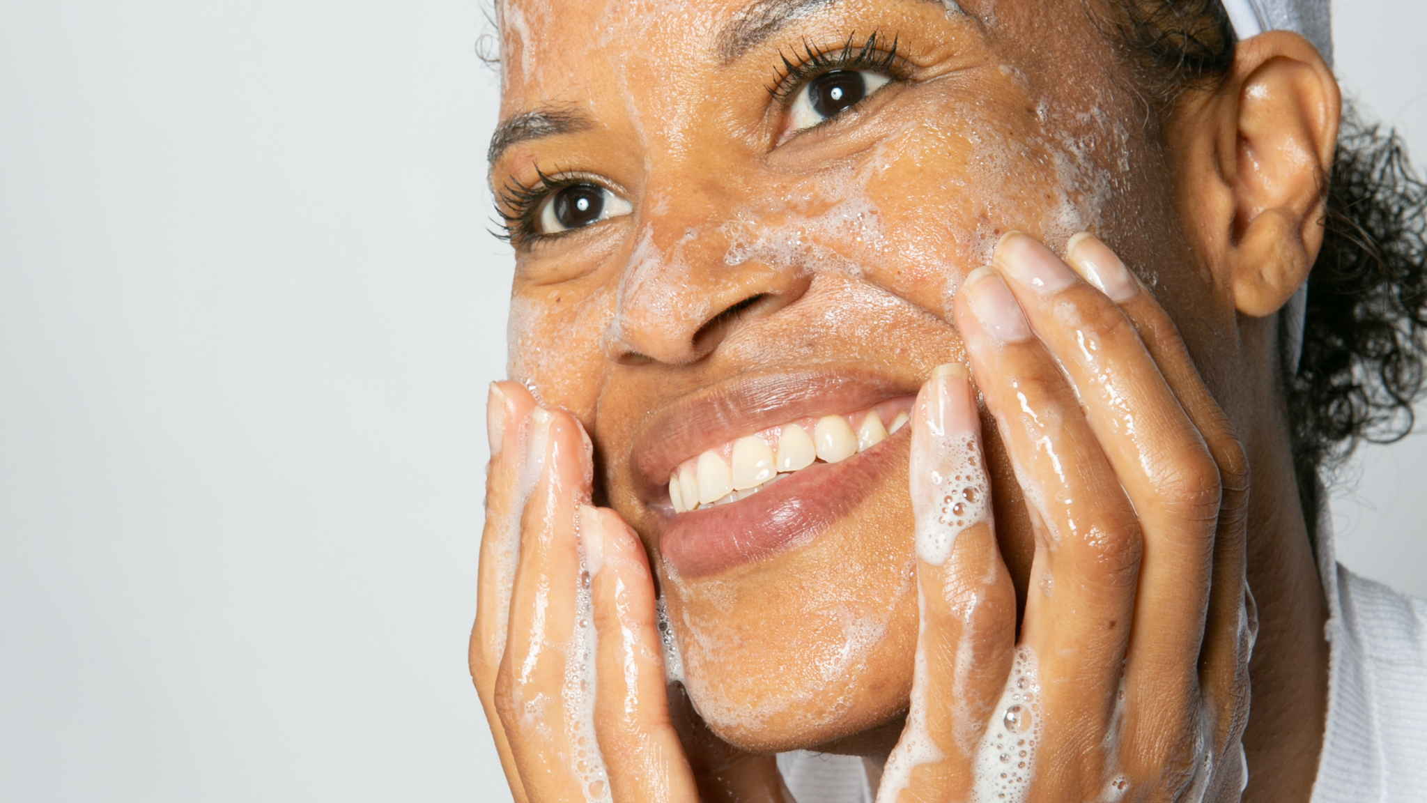 10 tips for clearer skin. a pretty, mature black woman sudsing her face up
