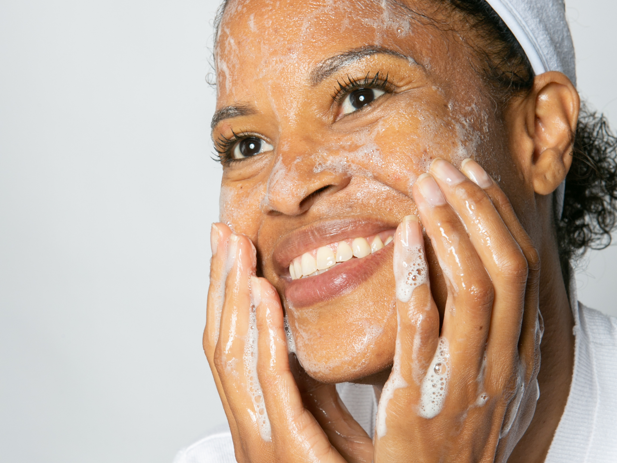 10 tips for clearer skin. a pretty, mature black woman sudsing her face up