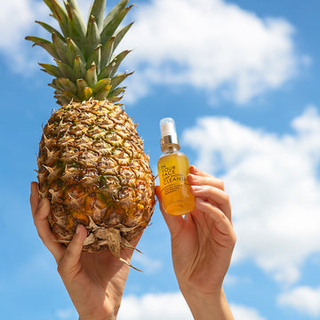 A hand in the sky holding the DEEP ENZYME CLEANSE and a pineapple. IN YOUR FACE DEEP ENZYME CLEANSE Uses Pineapple