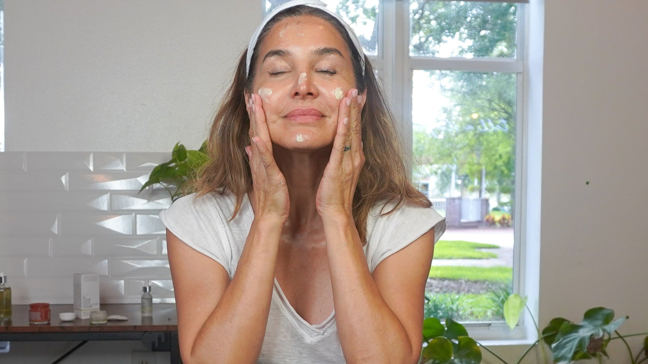 a woman applying skincare to her face, looking relaxed