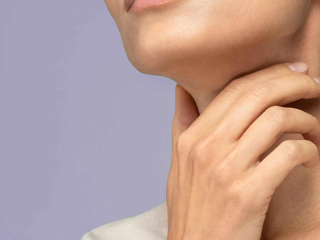 a woman holding her neck on a purple background