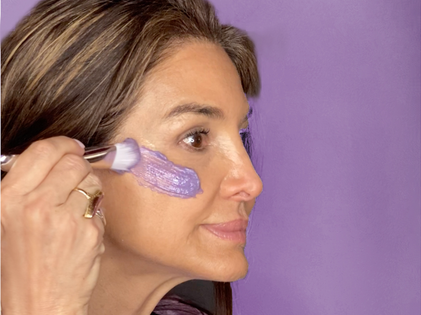 woman applying a purple face mask to her cheek