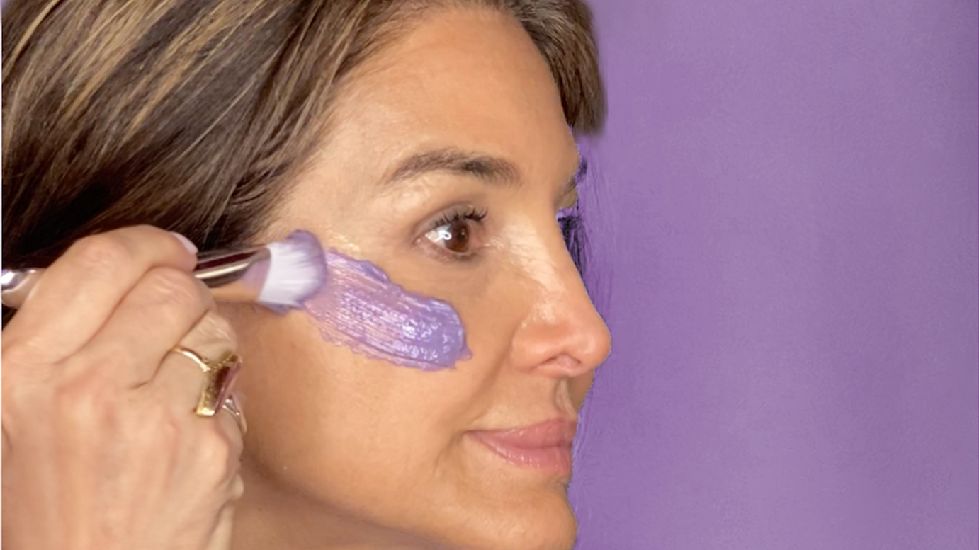 woman applying a purple face mask to her cheek