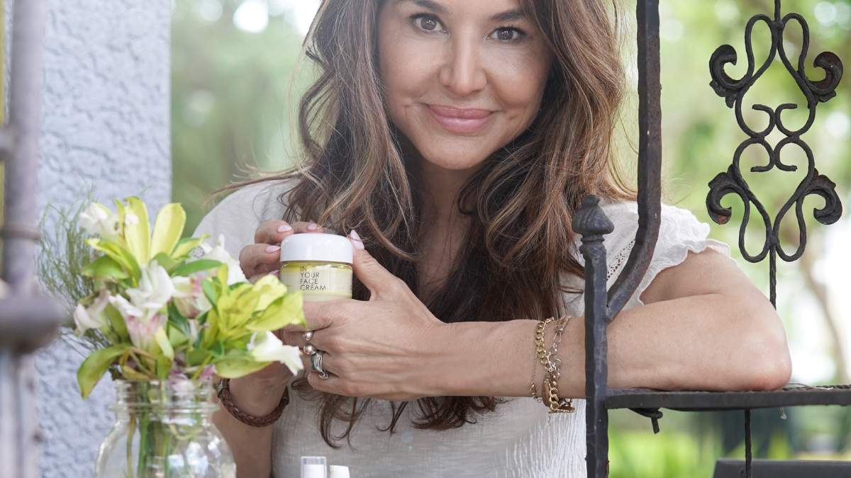 a woman holding onto various skincare products outside