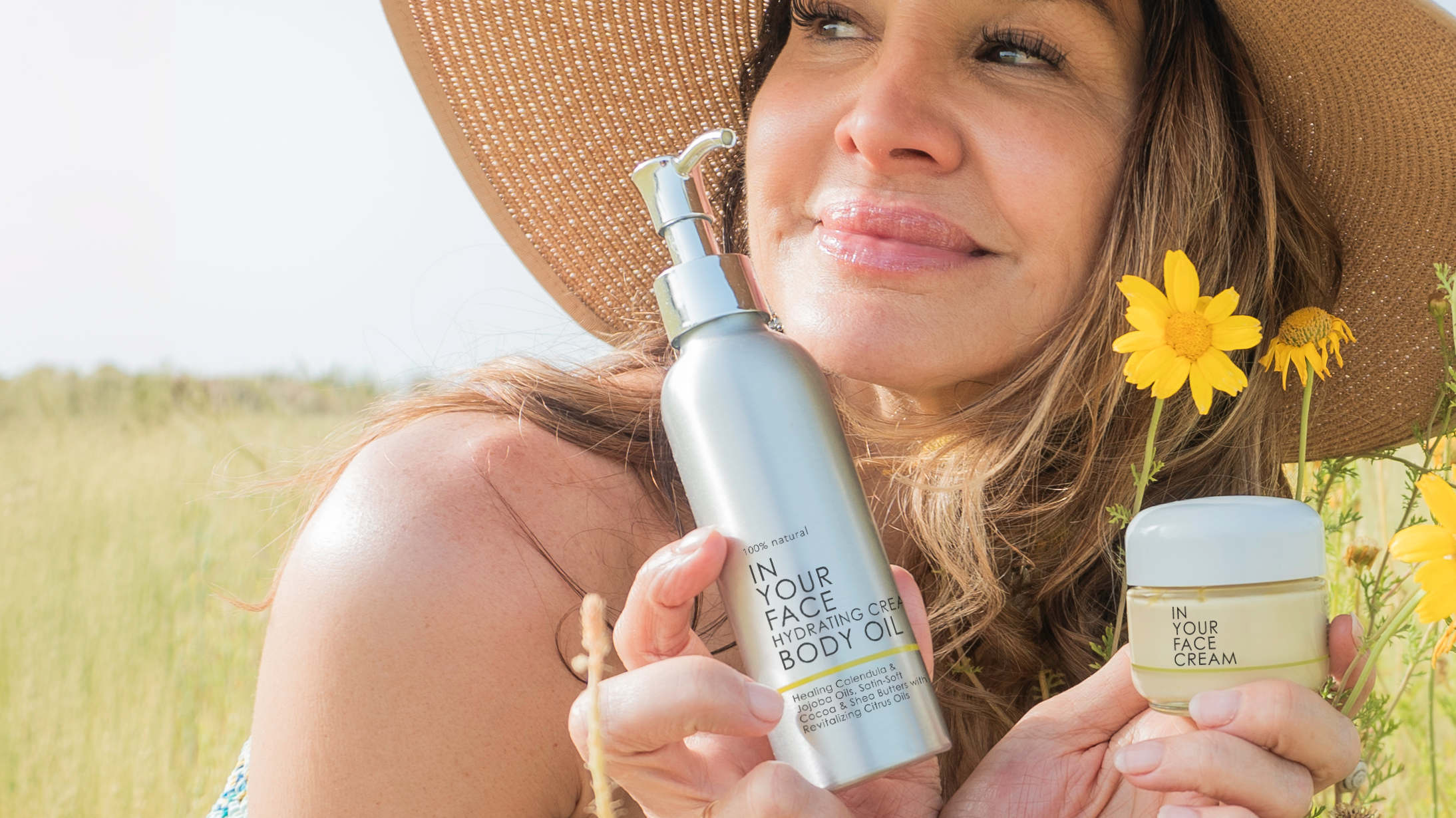 Denice with sun hat in field w/ CREAM & BODY OIL 