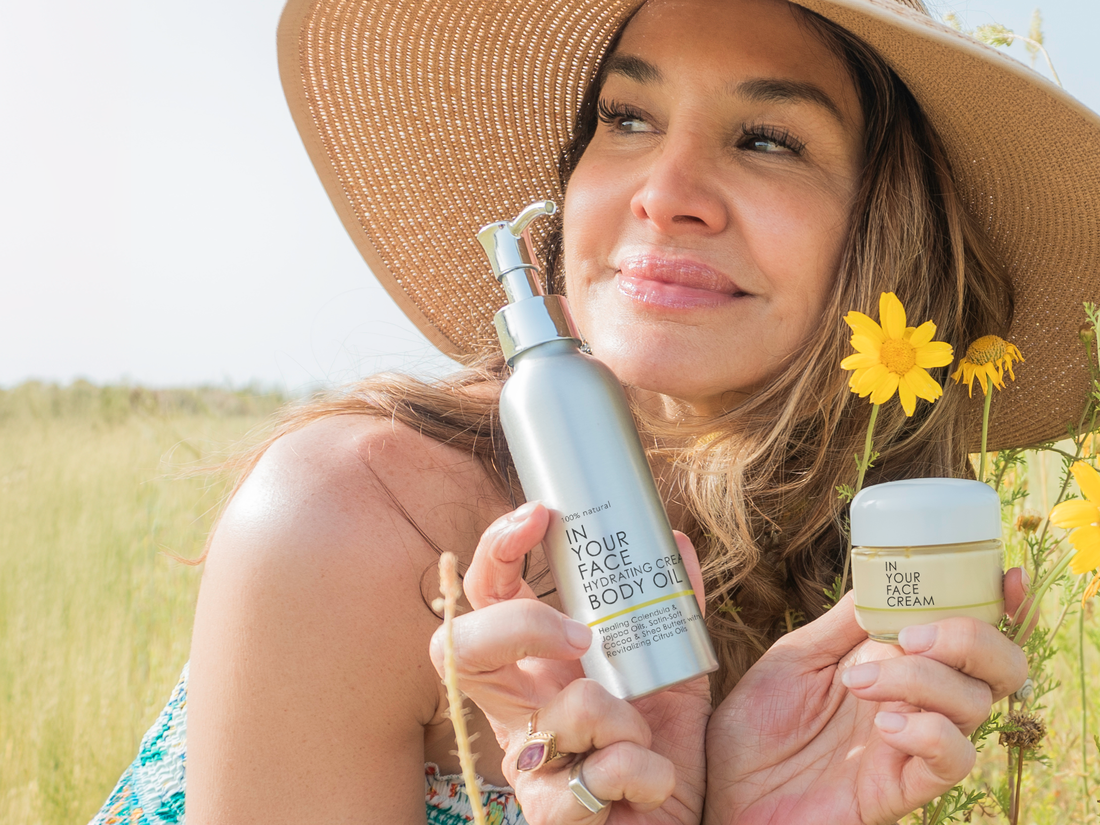 Denice with sun hat in field w/ CREAM & BODY OIL 