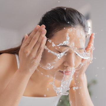 an asian woman splashing her face with water