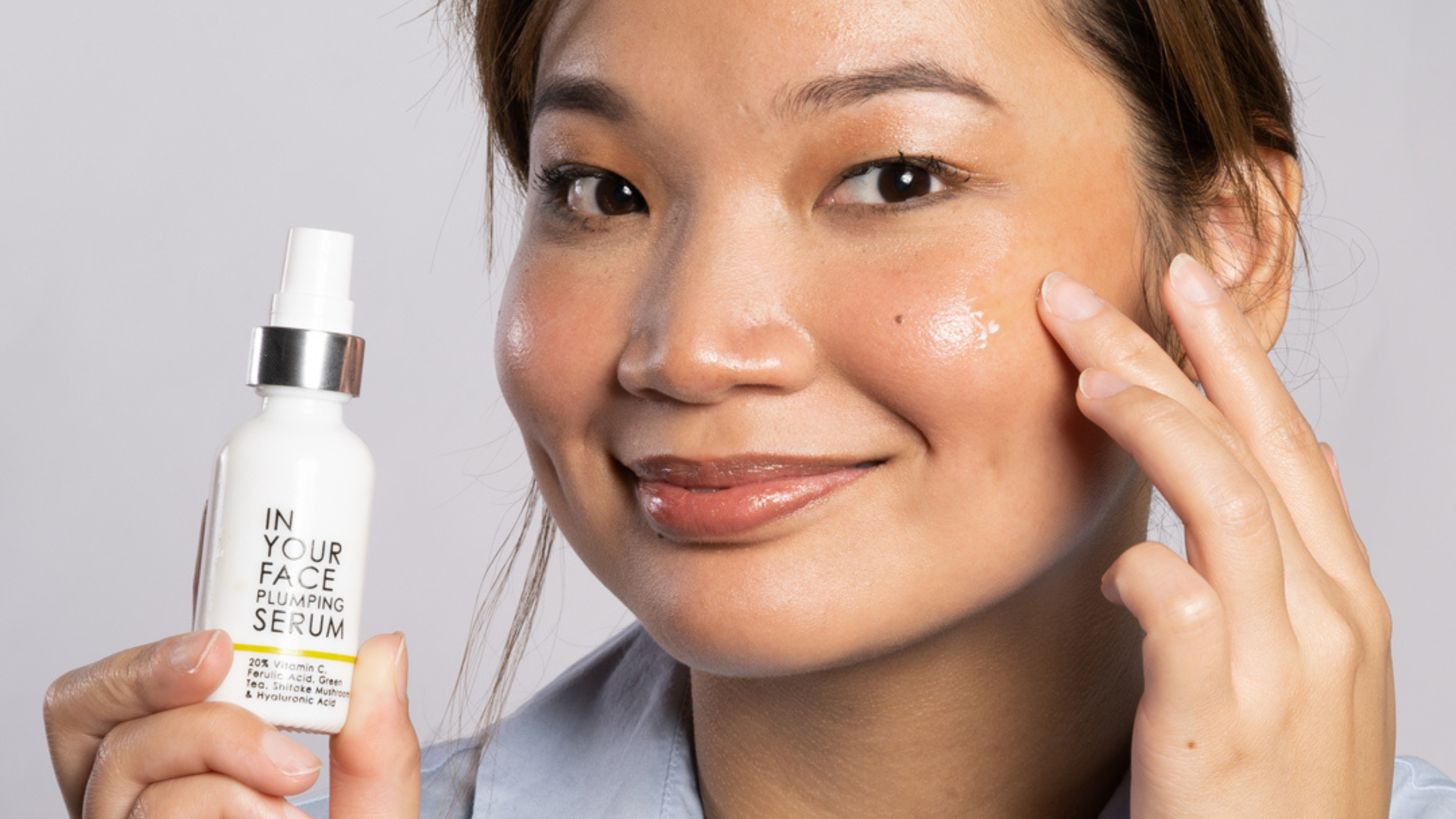 young woman holding up the PLUMPING SERUM