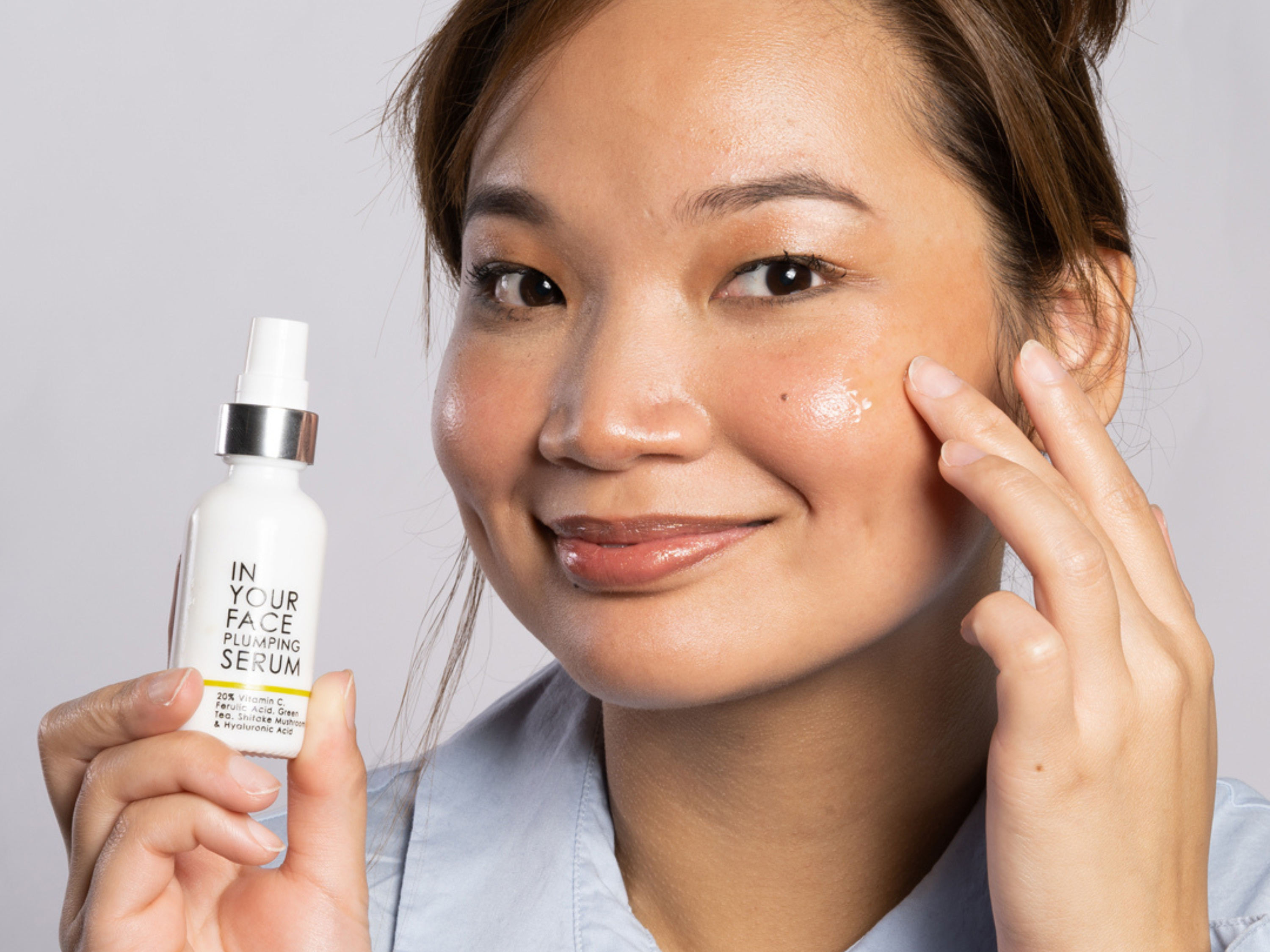 young woman holding up the PLUMPING SERUM