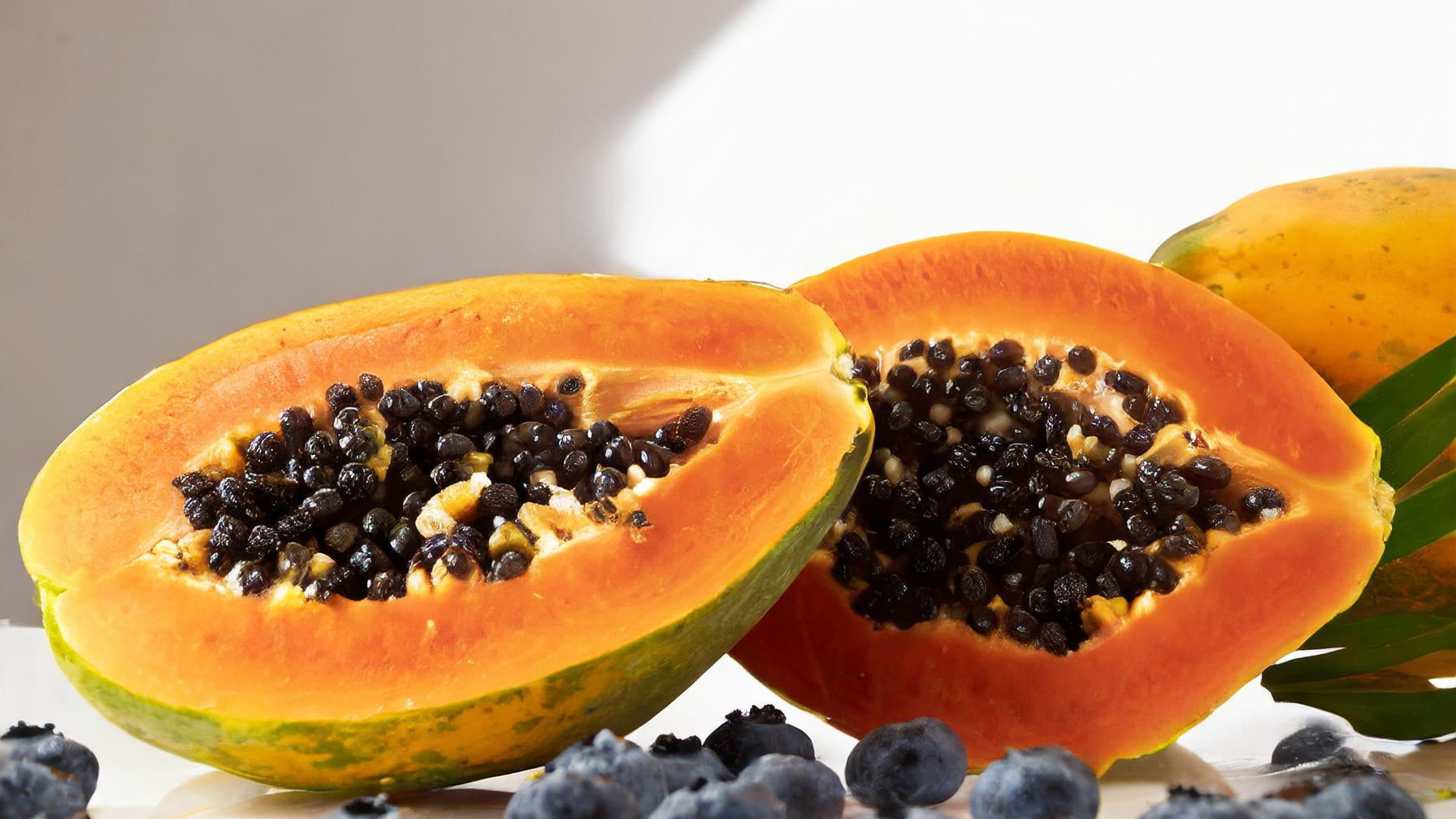 blueberries and sliced papaya on a white background