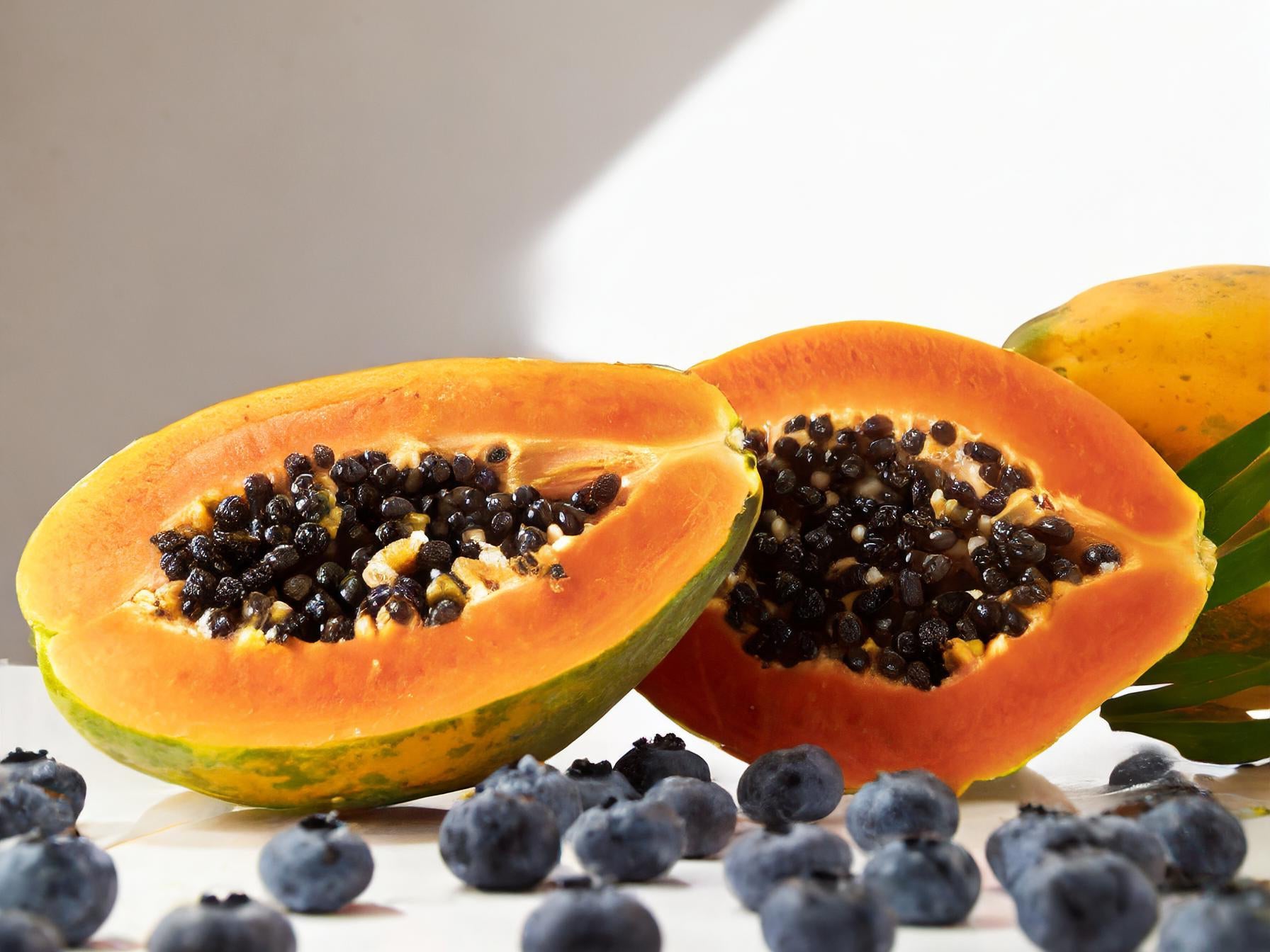blueberries and sliced papaya on a white background