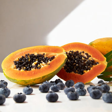blueberries and sliced papaya on a white background