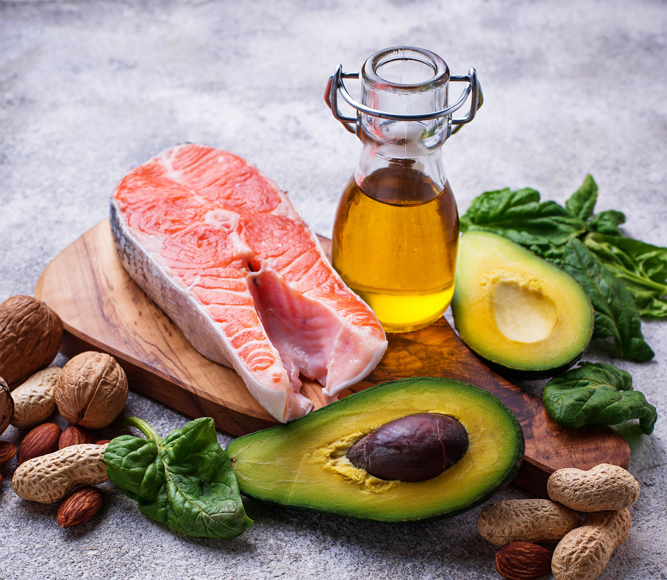 an jar of olive oil surrounded by foods with healthy fats like salmon and avocados