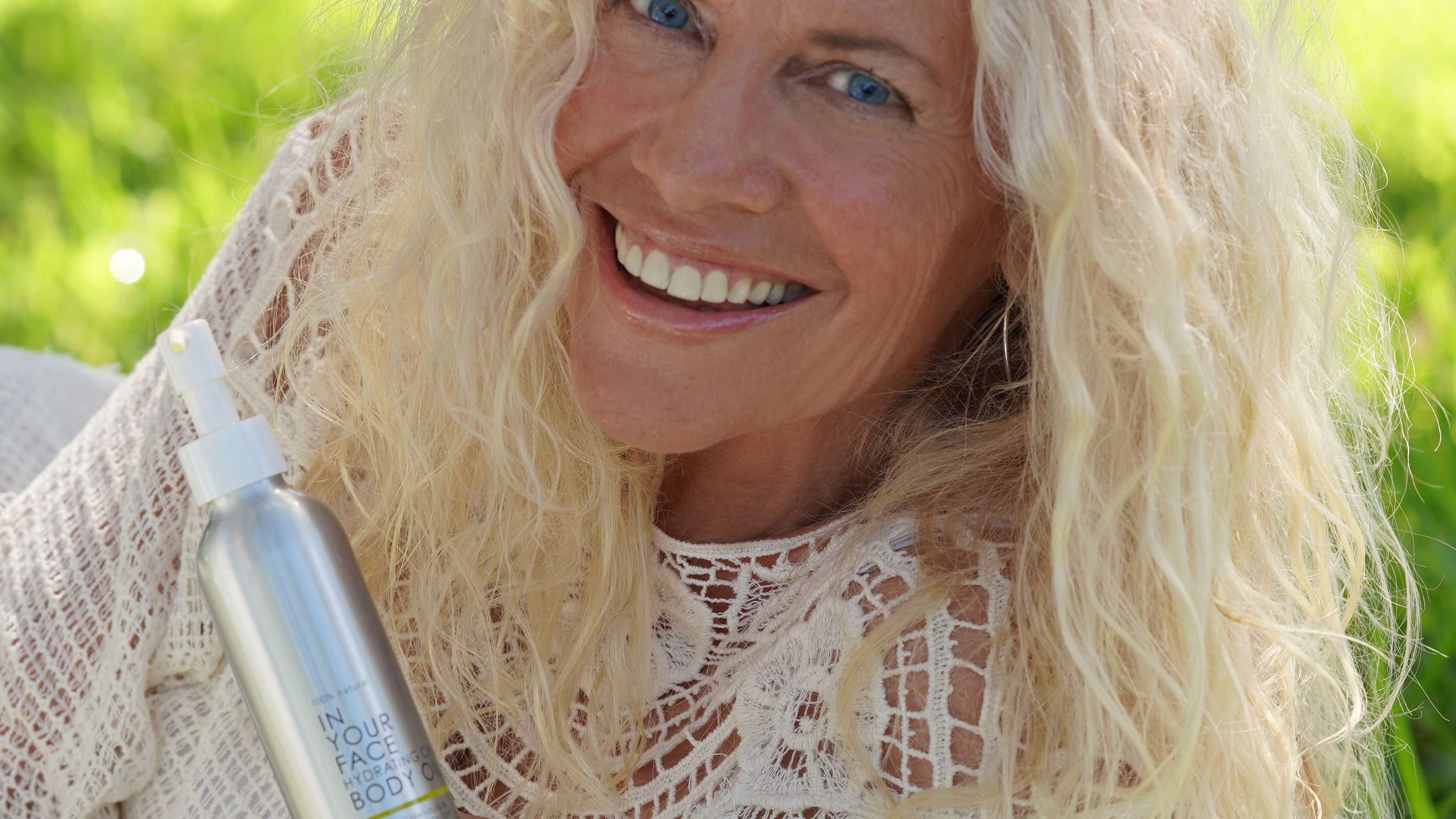 an older woman holding CREAMY BODY OIL and smiling