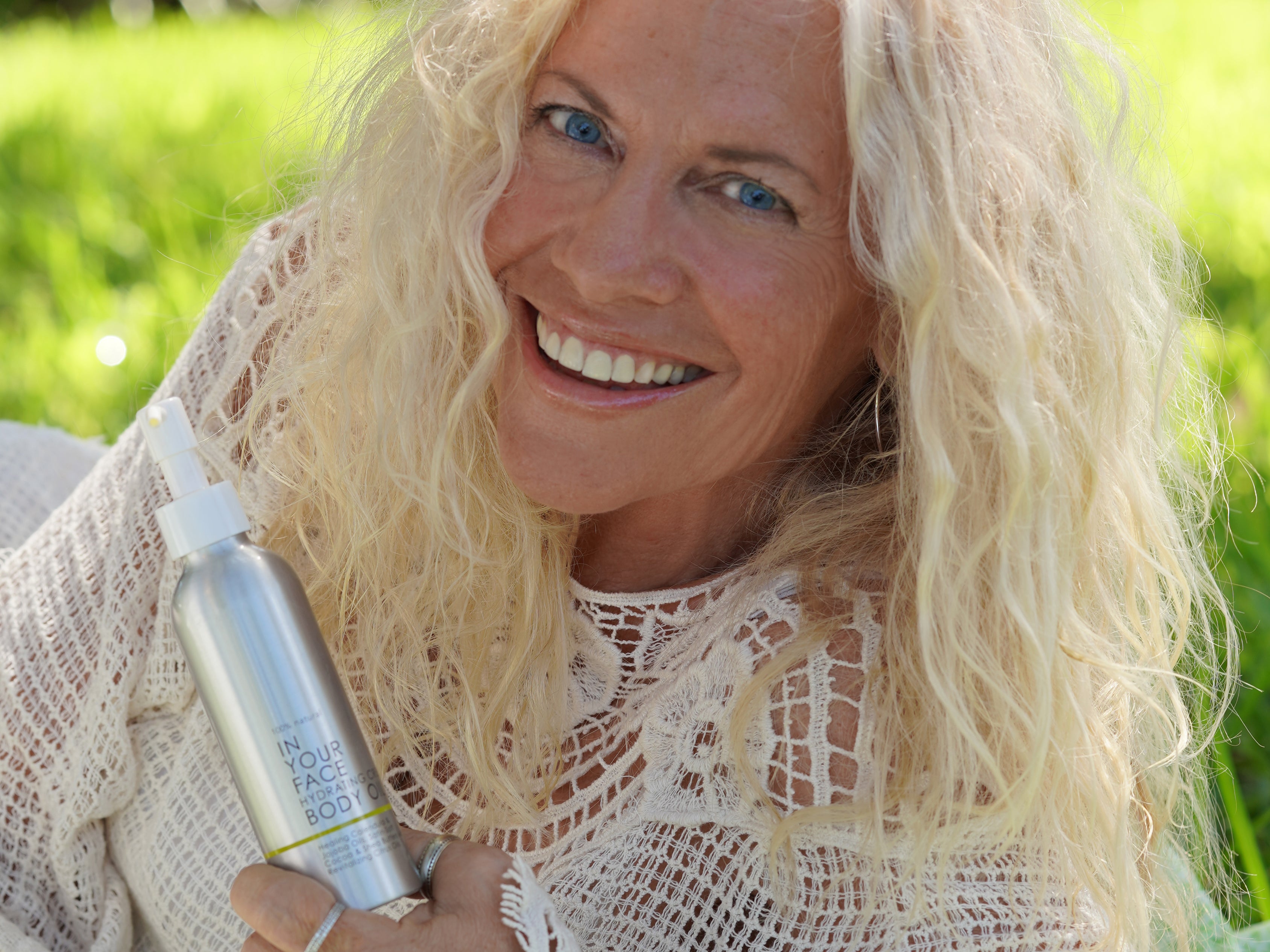 an older woman holding CREAMY BODY OIL and smiling