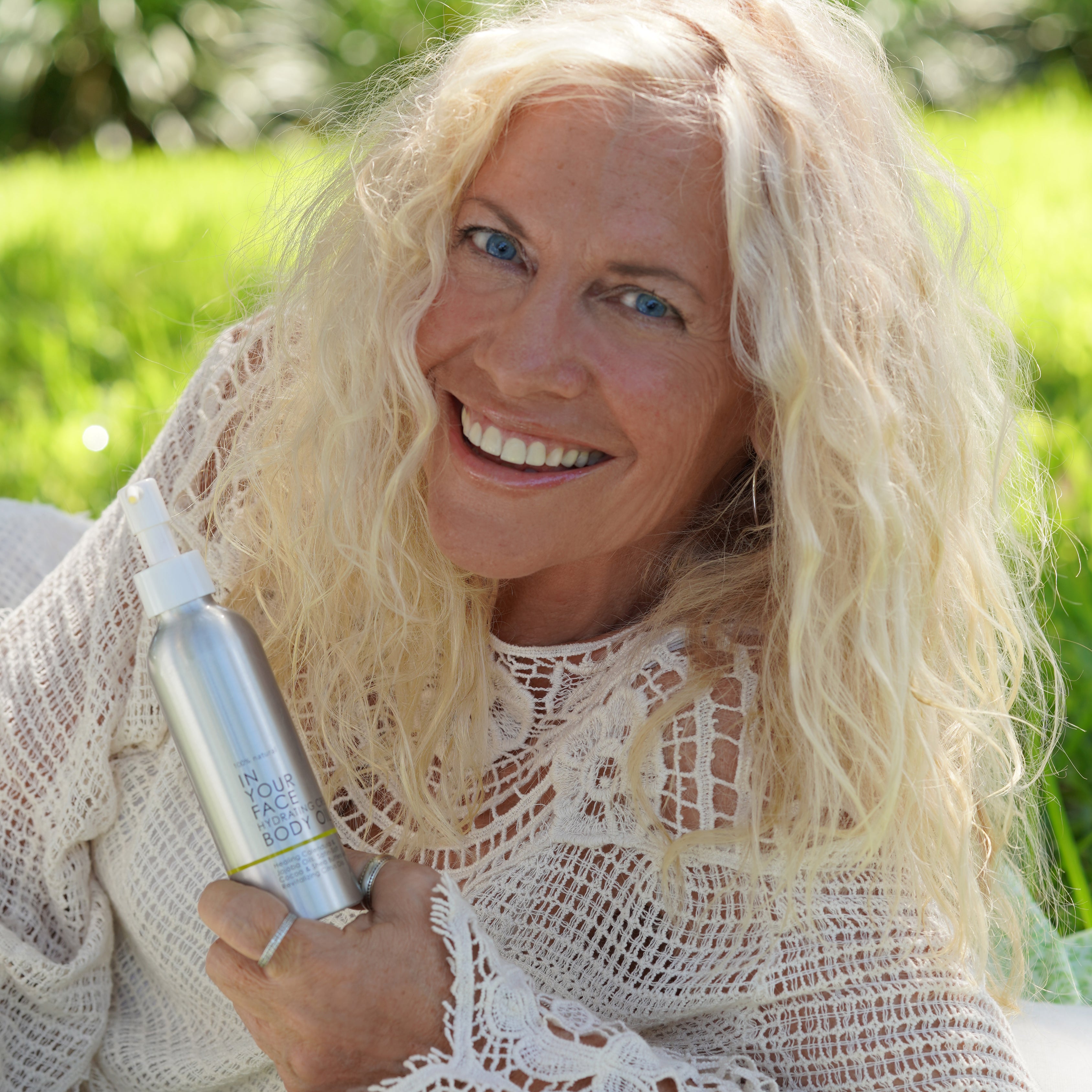 an older woman holding CREAMY BODY OIL and smiling
