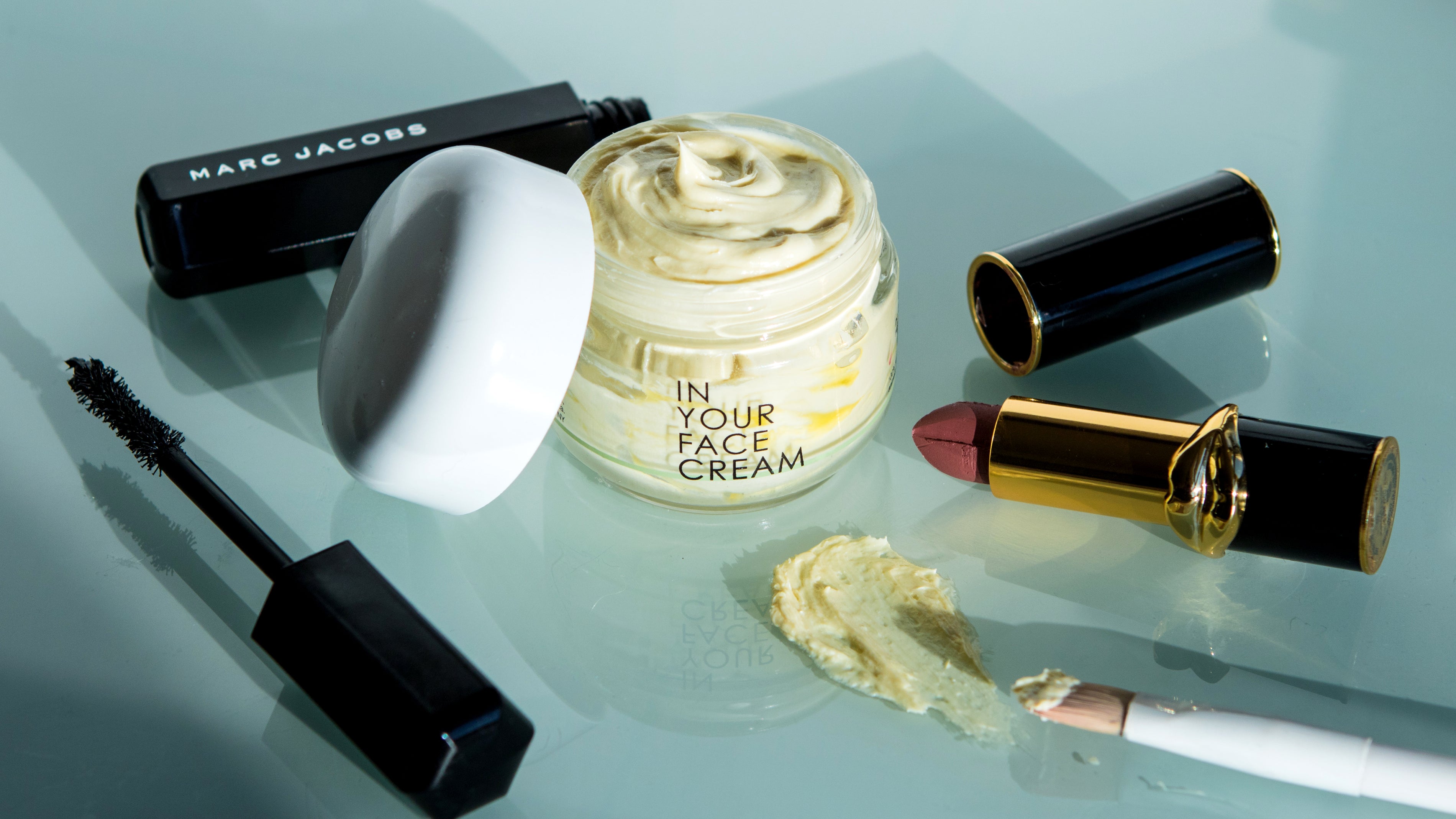 THE CREAM surrounded by luxury makeup products