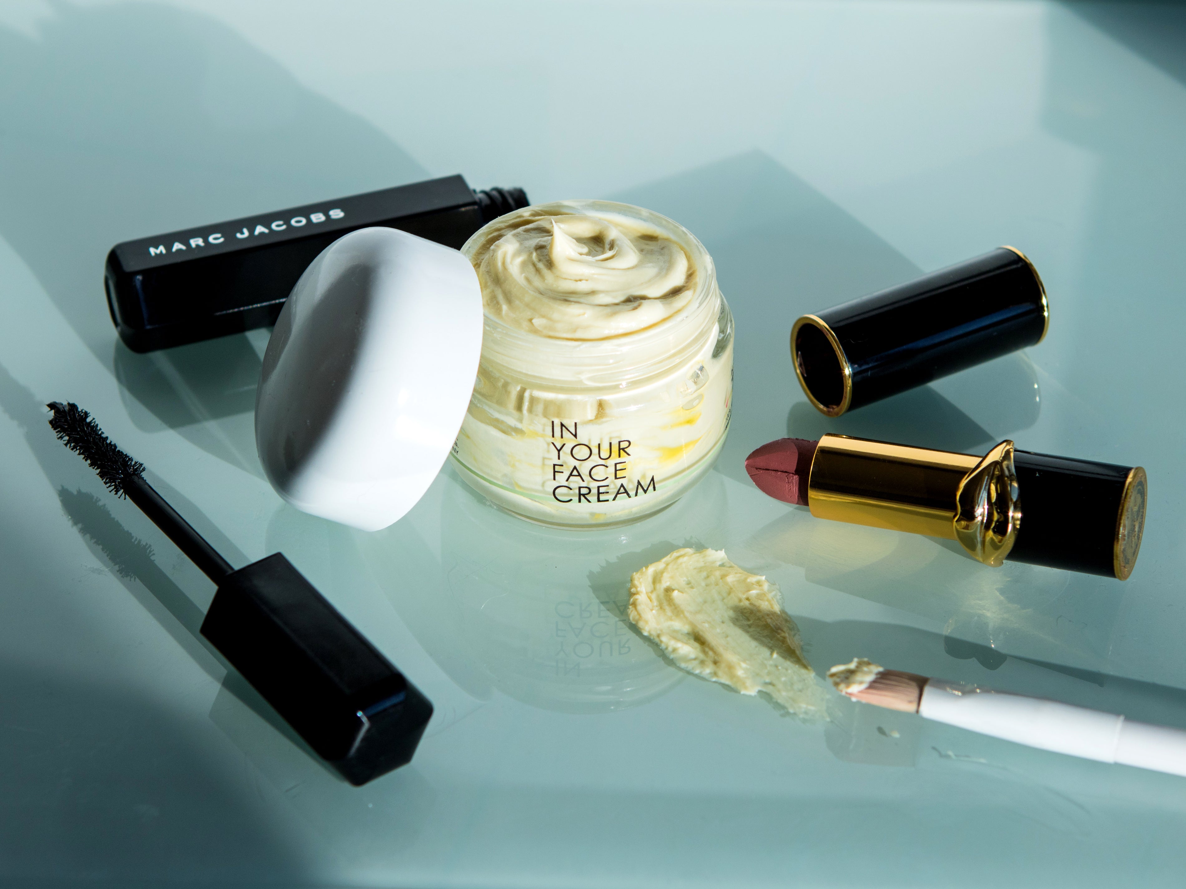 THE CREAM surrounded by luxury makeup products