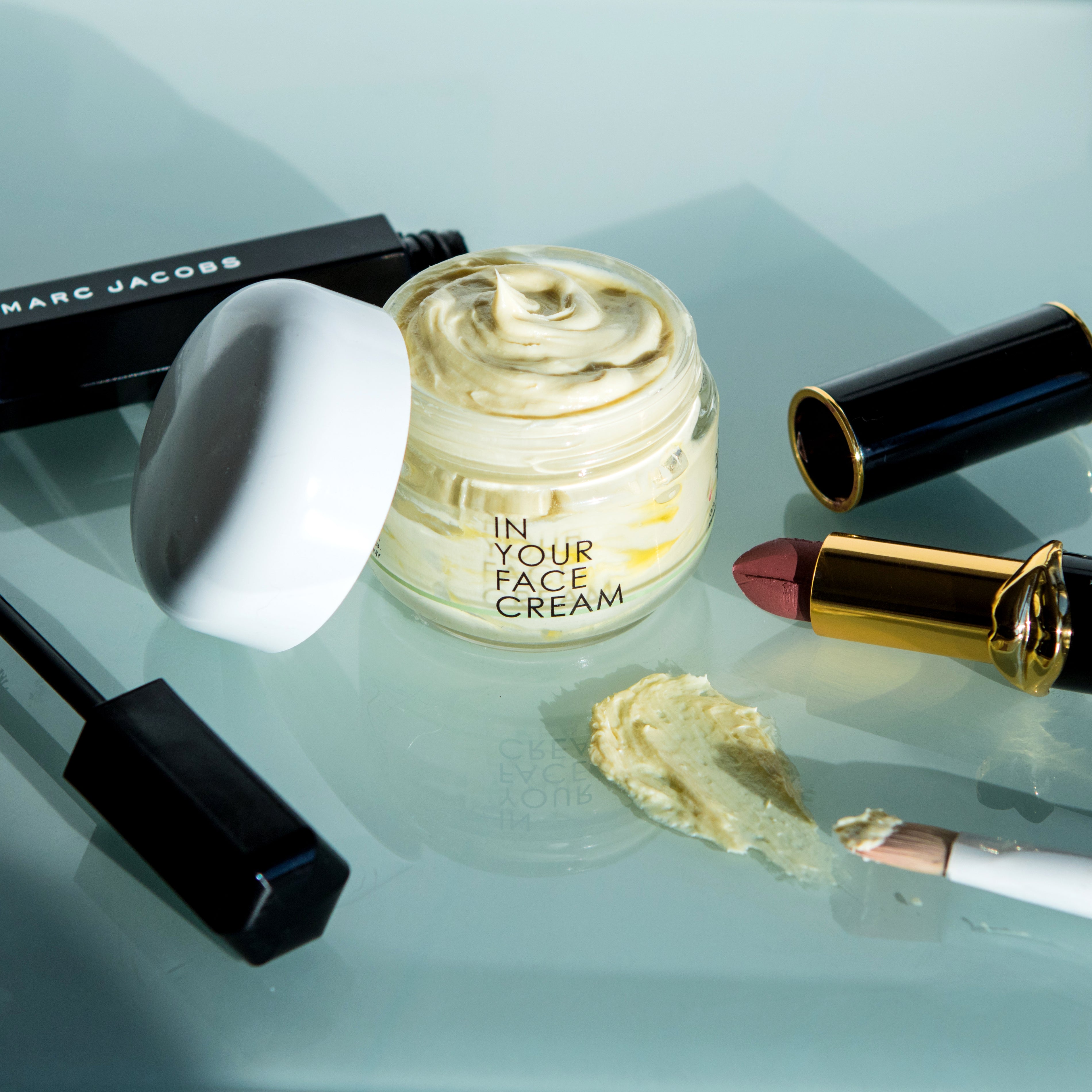 THE CREAM surrounded by luxury makeup products