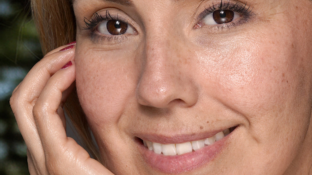 Closeup of woman looking into camera holding face with one hand