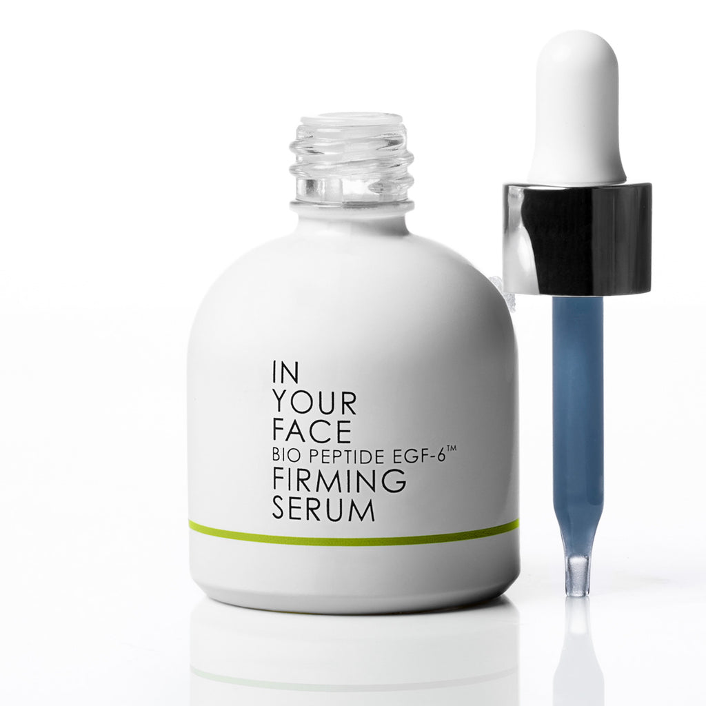 A white bottle of In Your Face Bio Peptide EGF-6 Firming Serum next to a blue glass dropper with a black collar, on a clean white background.