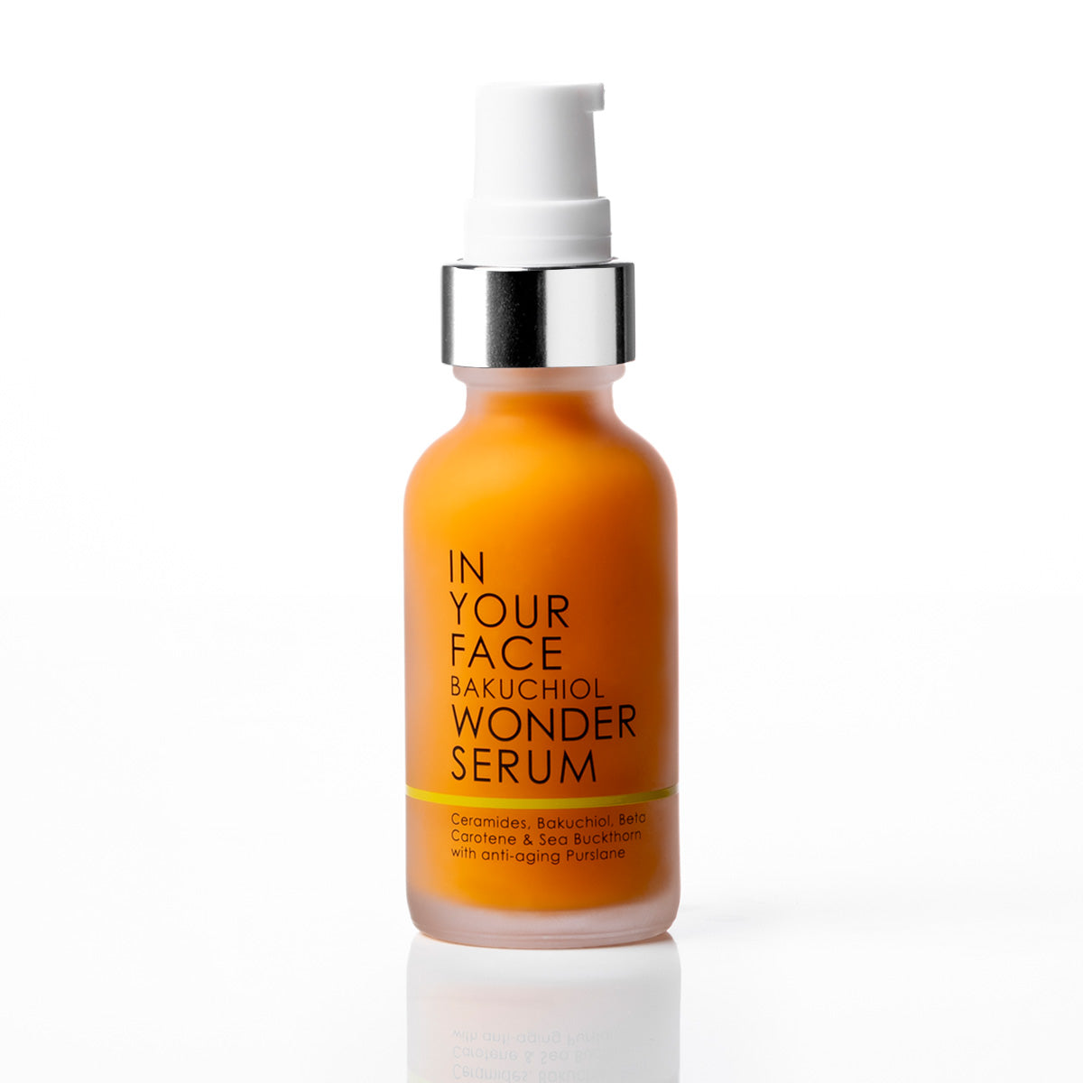 A bottle of IN YOUR FACE BAKUCHIOL WONDER SERUM with an orange body, a silver collar, and a white pump dispenser, set against a clean white background with a soft reflection.