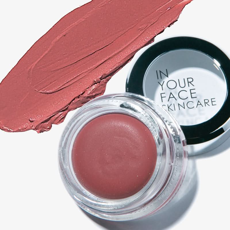 Pink cosmetic cream in a jar with a swatch of color next to it, branded 'In Your Face Skincare'.