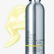 Silver bottle of 'In Your Face Hydrating Creamy Body Oil' with yellow oil smear on white background