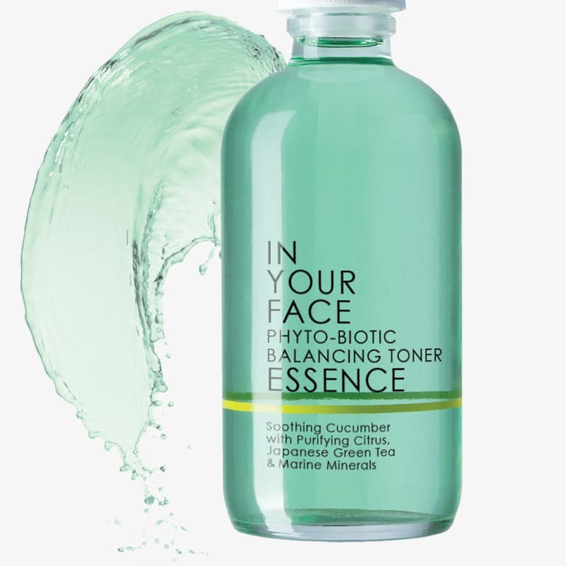 Bottle of 'In Your Face' toner essence with a splash of liquid on a white background