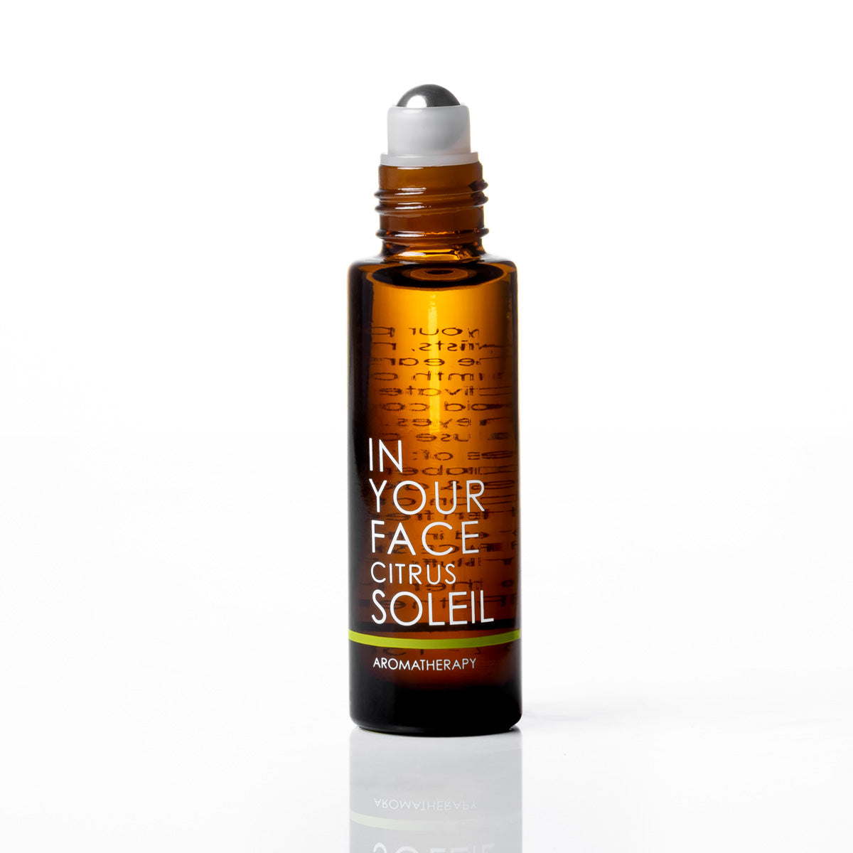 An amber glass rollerball bottle with a white cap, labeled 'IN YOUR FACE CITRUS SOLEIL' by Aromatherapy, set against a clean white background with a soft reflection.