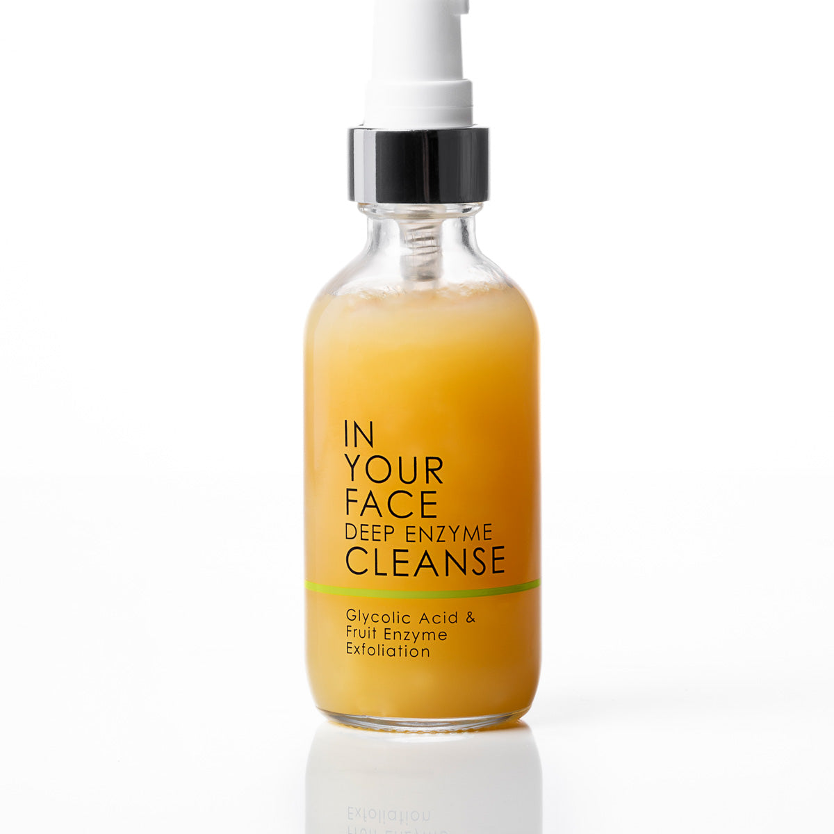 A clear glass bottle of IN YOUR FACE DEEP ENZYME CLEANSE with a white pump and black collar, filled with an orange-yellow liquid, on a white background with a soft reflection.