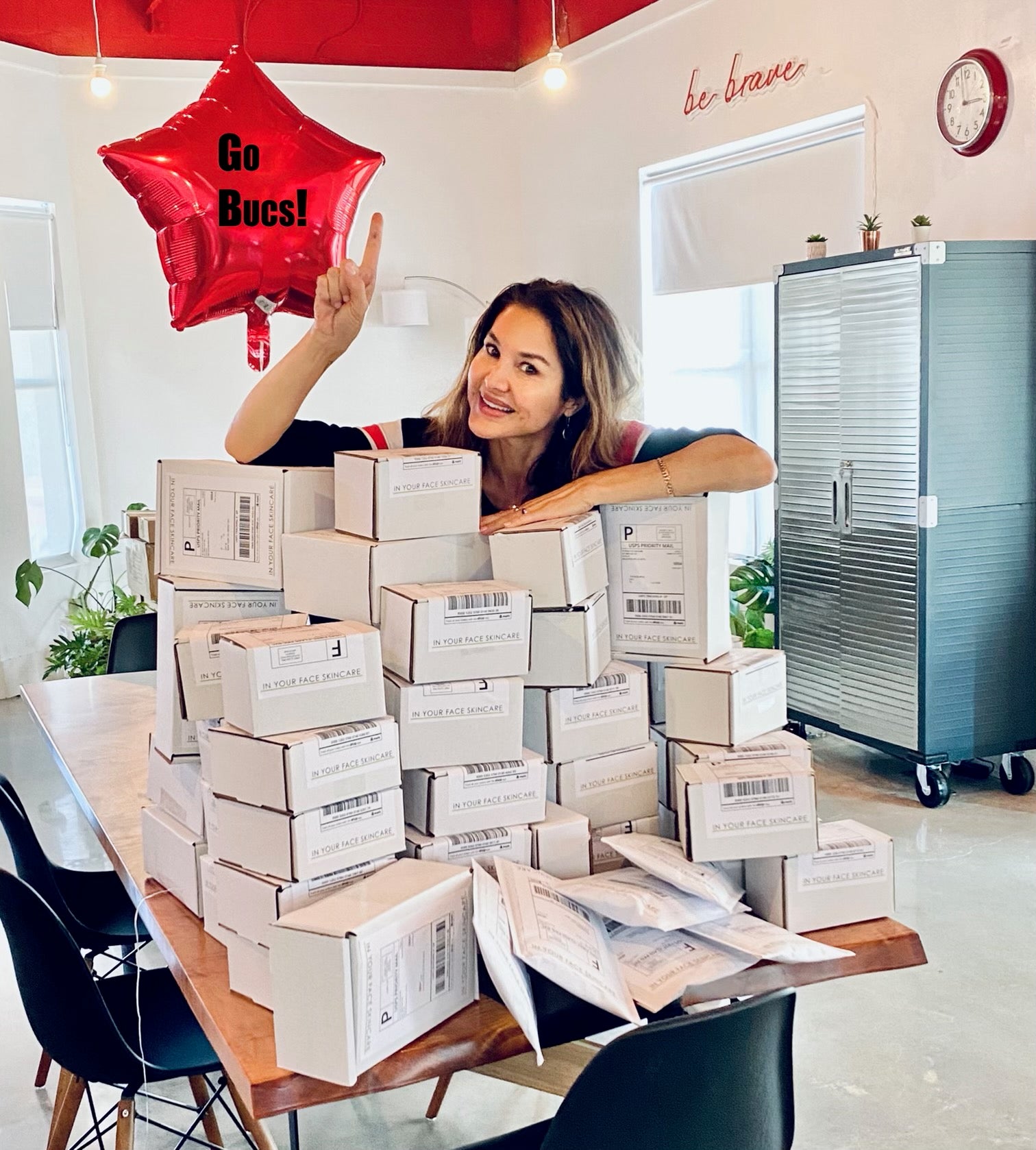 Denice with lots of packages for customers and a Go Bucs balloon
