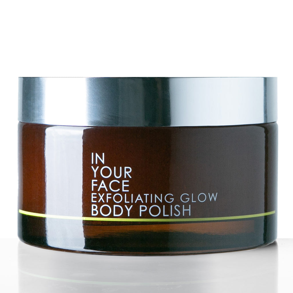 A dark brown jar of 'In Your Face Exfoliating Glow Body Polish' with a reflective silver lid, set against a clean white background.