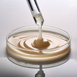 Close up image of creamy oil dripping into a petrie dish