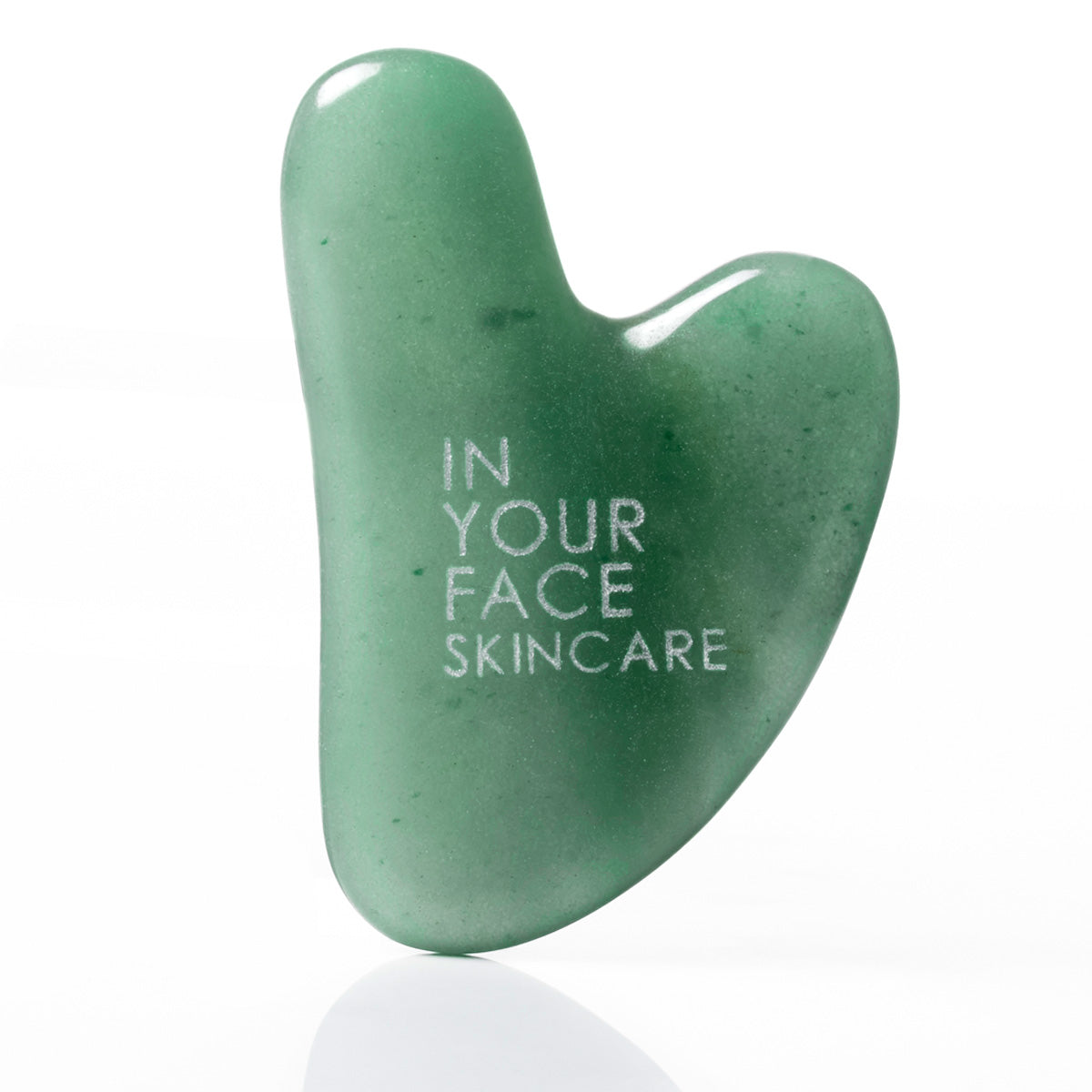A green jade facial gua sha massage tool with the brand name 'IN YOUR FACE SKINCARE' printed in white on its smooth, polished surface, set against a clean white background with a soft reflection below.